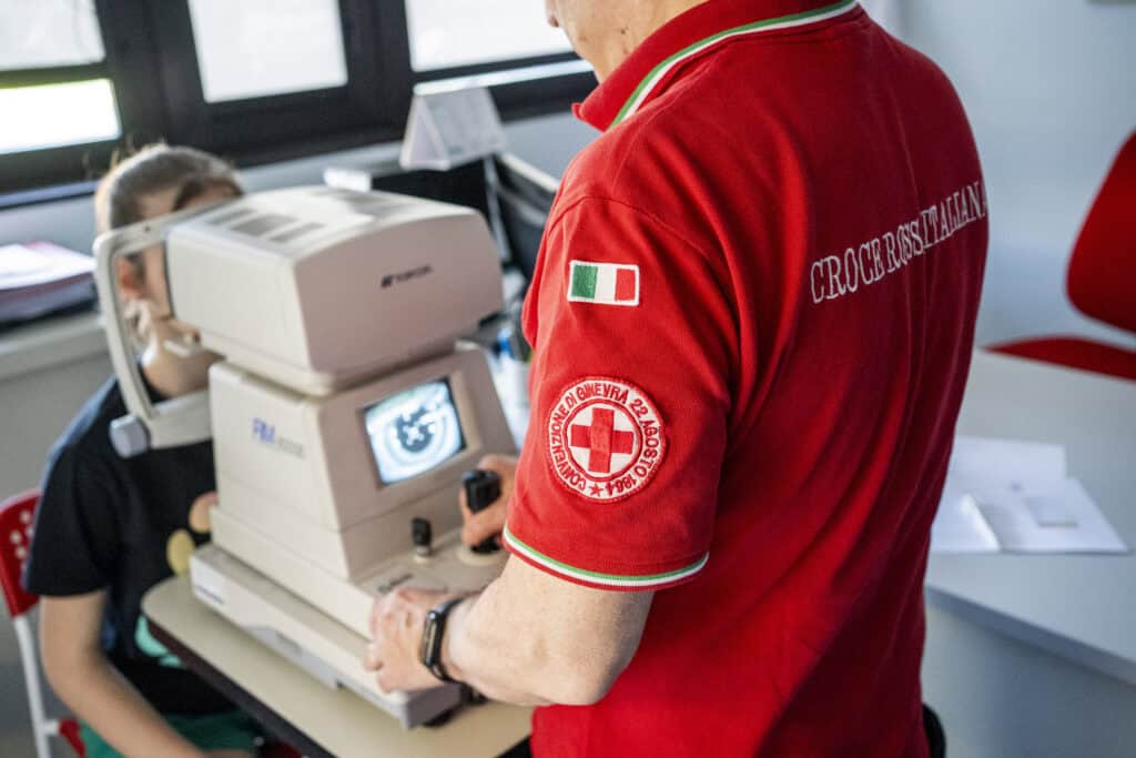 A Red Cross worker performs a visual screening on a little girl