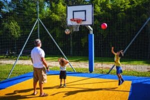 un papà e due bambini giocano a basket nel campo sportivo inclusivo del parco