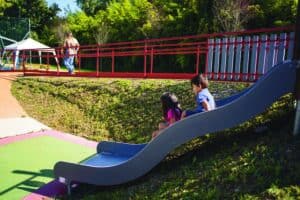 due bambini scendono dallo scivolo inclusivo del parco