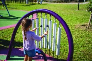 una bambina suona con i martelletti il grande xilofono del parco inclusivo